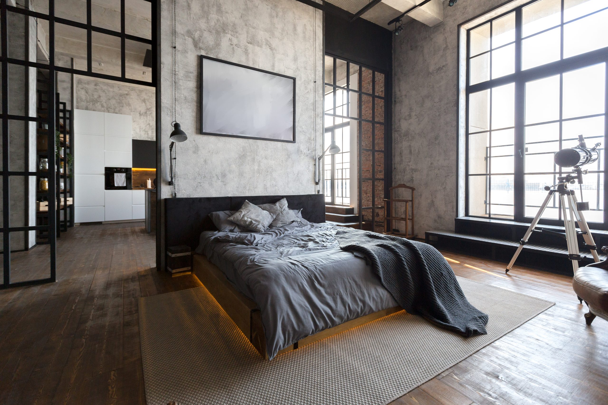 luxury studio apartment with a free layout in a loft style in dark colors. Stylish modern kitchen area with an island, cozy bedroom area with fireplace and personal gym
