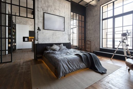 luxury studio apartment with a free layout in a loft style in dark colors. Stylish modern kitchen area with an island, cozy bedroom area with fireplace and personal gym